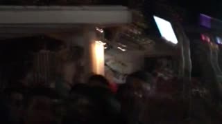 Guy in white shirt jumps into crowd while filming on phone