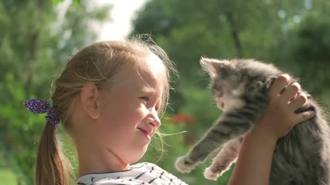 Cute little child blond girl with kitten, girl playing with cat in the summer park
