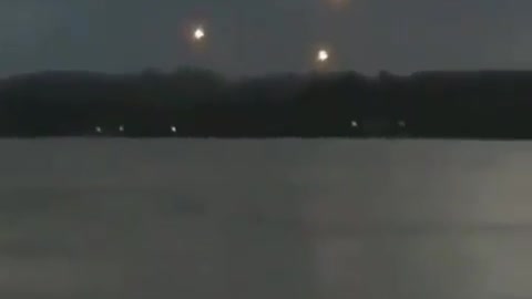 People looking at a lake, seeing lights in the sky like UFOs