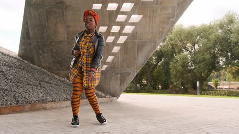 A Woman Dancing Freely Outdoors On A Concrete Pavement