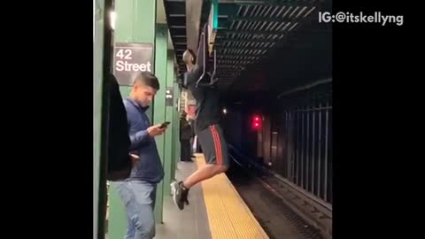 Man works out at a subway station, does pull ups on ceiling sign