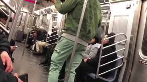 Green jacket and hat guy plays violin on the subway car