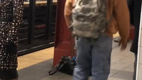 Man charging next to red pole in subway