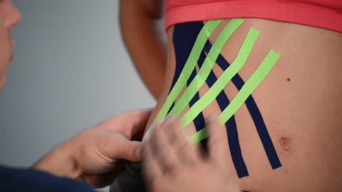 Putting kinesio tape on an athlete's hip