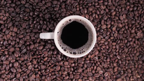 Cup of coffee on top of coffee beans