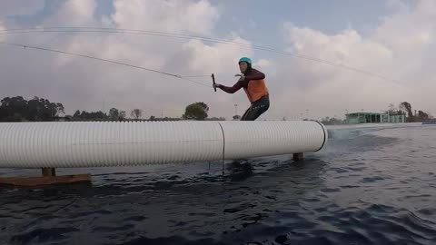 Guy wakeboarding tries to do trick but slams body into white pipe and falls into water
