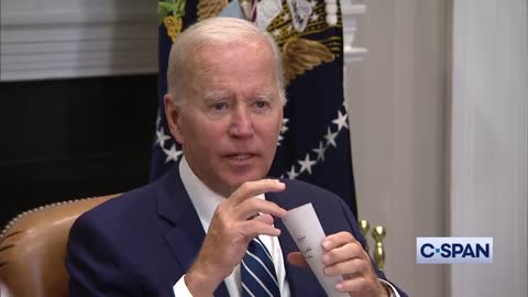 President Joe Biden holds up a note card of instructions