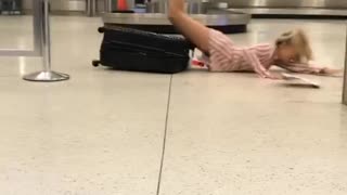 Girl in airport balancing on luggage falls on stomach