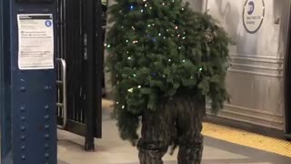 Man dressed as christmas tree walking subway station
