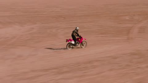 Aerial tracking of a man on a motorcycle in the desert.