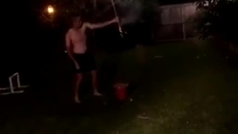 Shirtless guy in a backyard sets off fireworks