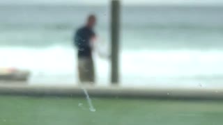 Guy washing his board at the beach shower