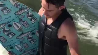 Impressive wake board surfer drinks a beer and does tricks behind boat
