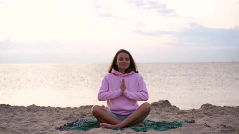 A Woman Sitting On The Beach While Meditating