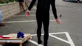 Guy in black outside tossing bean bag