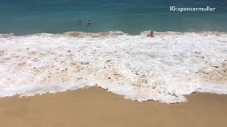 Three people surfboarding get wiped out by huge wave