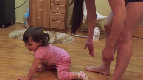 The little sister laughs funny at her older sister, when her mom stretches out