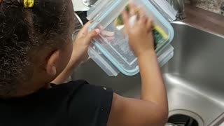 Baby girl is washing dishes