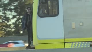 Train Hopping Fellow Waves to Traffic