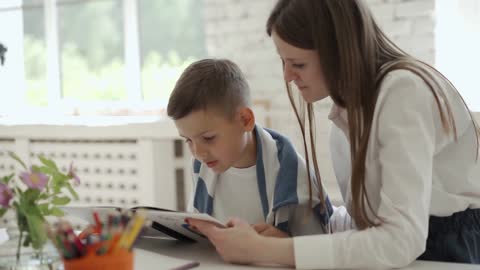 A Female Teacher Reading a Book with a Male Student