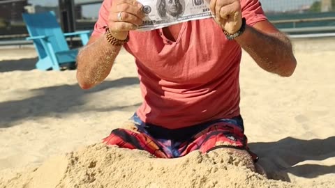 A Man Digging Money From The Sand