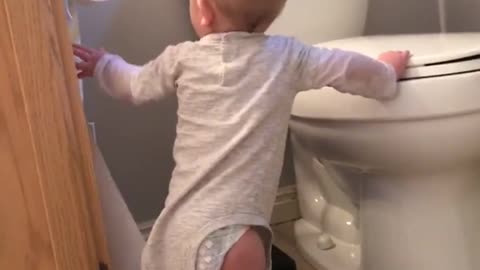 Baby pulling out roll of toilet paper, loses balance and face hits toilet