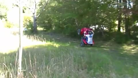 Helmet guy wheelies red four wheeler in grass and falls off