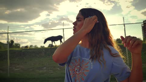 Young woman placing a flower on her ear in a sunset