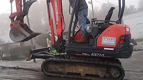 Loading a small excavator on the back of a rollback