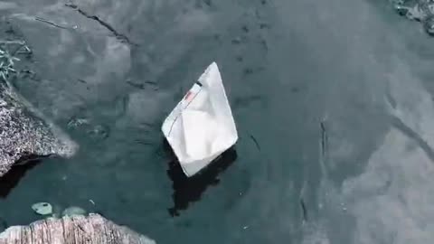 A Paper Boat Floating Over A Roadside Water Canal