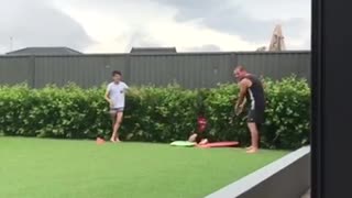 Kid sits on two boogie boards, gets pulled by brother and dad, and crashes into a bush