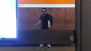 Guy dancing sunglasses headphones across subway station platforms