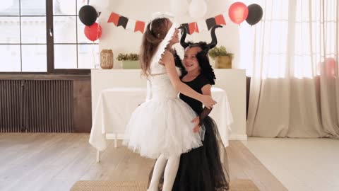 Two Little Girls Wearing Halloween Costumes and Hugging
