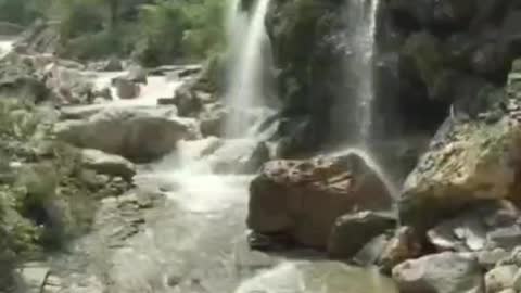 A small waterfall coming down from above converges into a river