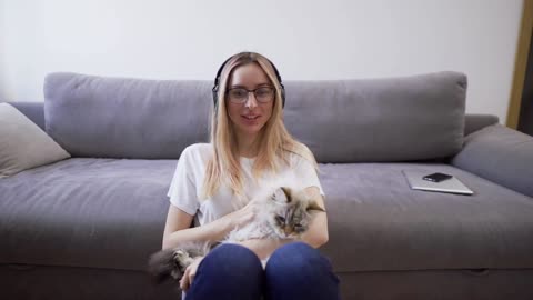 Webcam view woman in headphones hugs cat shoots video for blog with pet