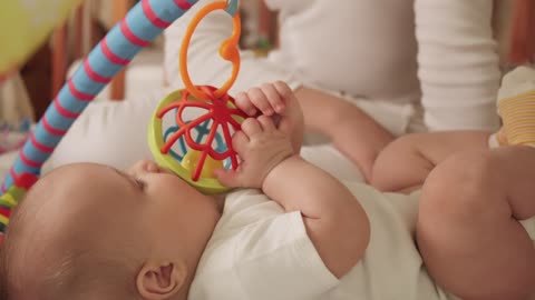 Little baby playing with toys in bed