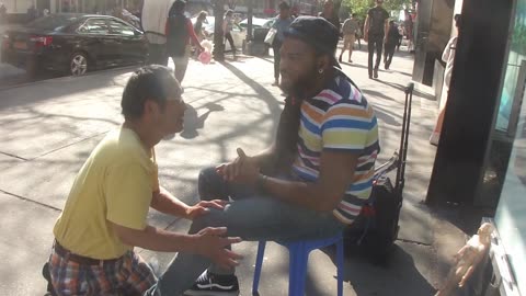 Luodong Massages Black Man's Knee On Sidewalk