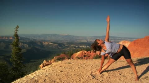 A beautiful girl doing yoga on a mountain top in the air amidst wonderful landscapes