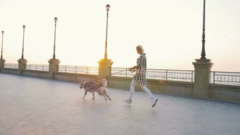 Young female running with siberian husky dog on sea front at sunrise, slowmo