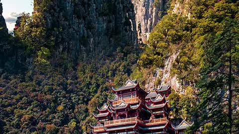 A boulder juts out from the green peaks and clouds, like a beautiful and moving maiden