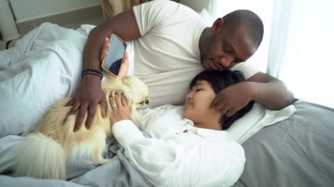 A Couple Talking while in Bed With Their Pet Dog