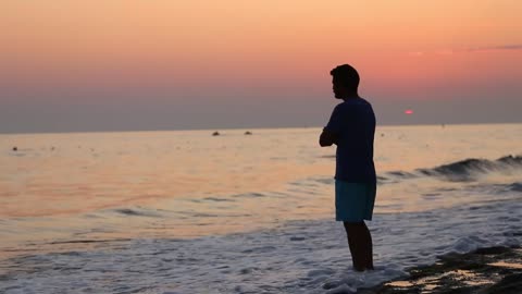 Lonely and brooding man on the shore of a beach