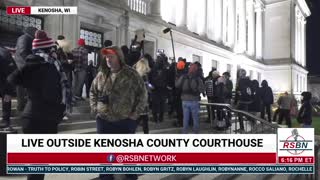 Protesters rip up someone’s sign and throw the pieces at her outside the courthouse in Kenosha