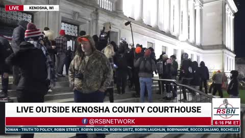 Protesters rip up someone’s sign and throw the pieces at her outside the courthouse in Kenosha