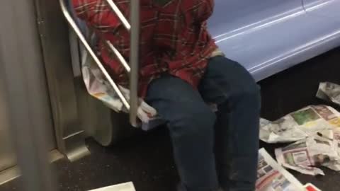 Red shirt guy surrounds self with newspapers and sleeps on subways