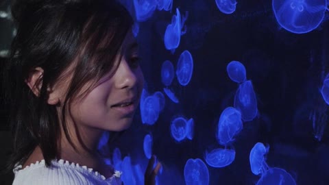 girl-looking-at-jellyfishes-in-an-aquarium