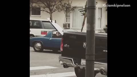 Blue convertible car drives around with white surfboard in it