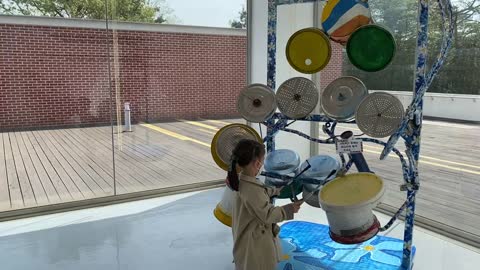 Little girl playing on recycled material drums