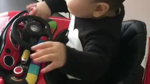 The baby is sitting on a toy car