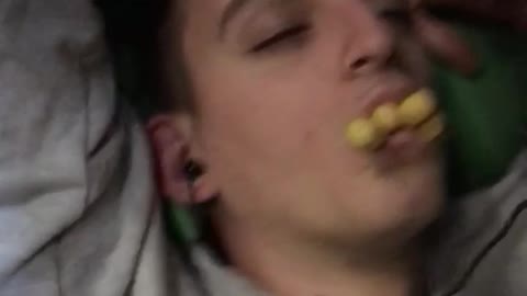 Sleeping guy in new york sweater gets crackers stuffed in his mouth